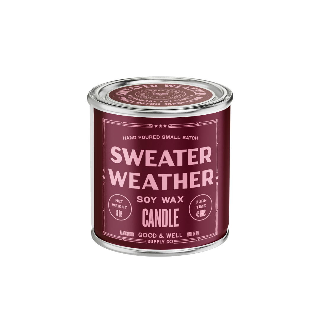 A cylindrical metal candle tin with a dark burgundy label reading 'SWEATER WEATHER' and 'SOY WAX CANDLE' on a plain white background.