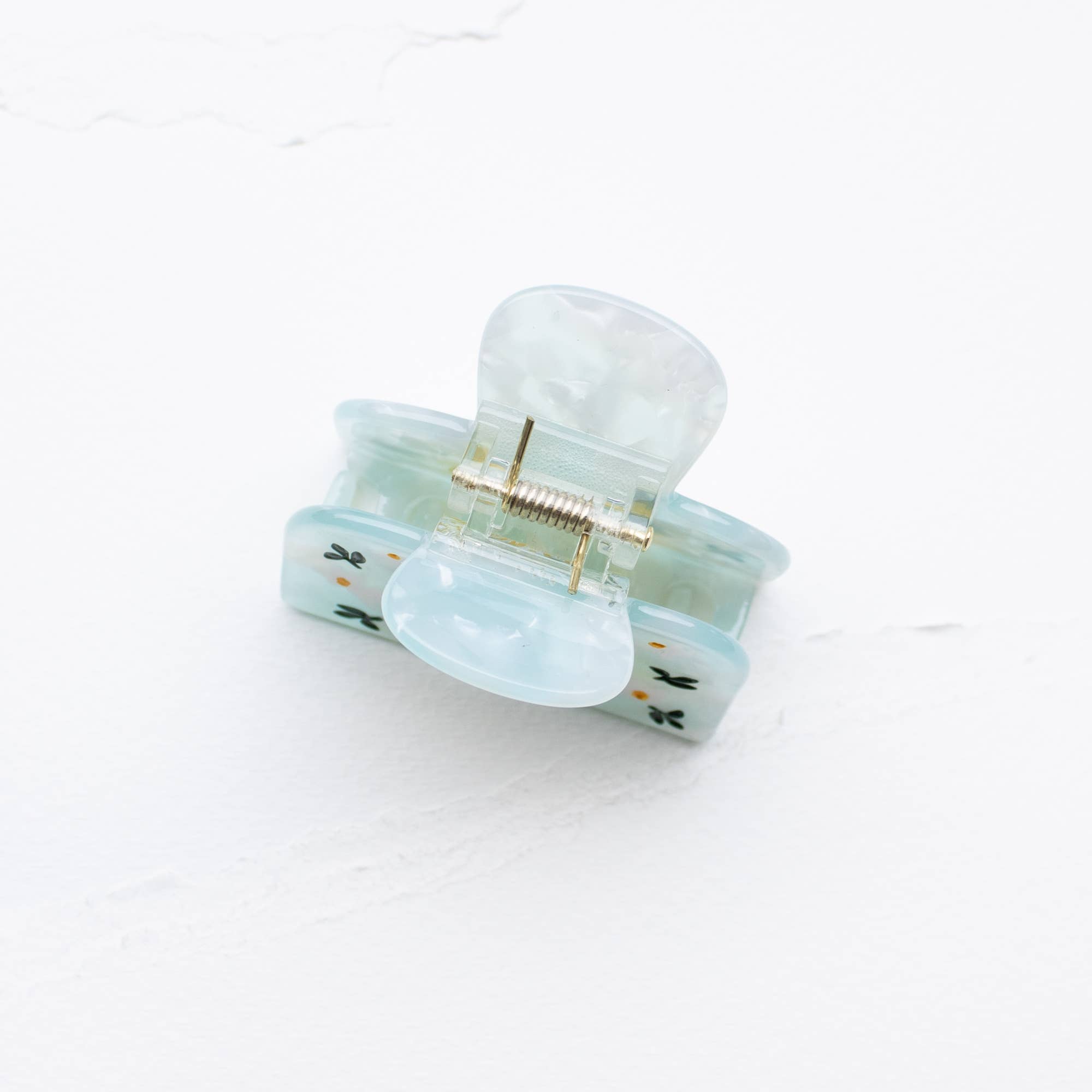 Light blue hair clip with gold accents on a white background