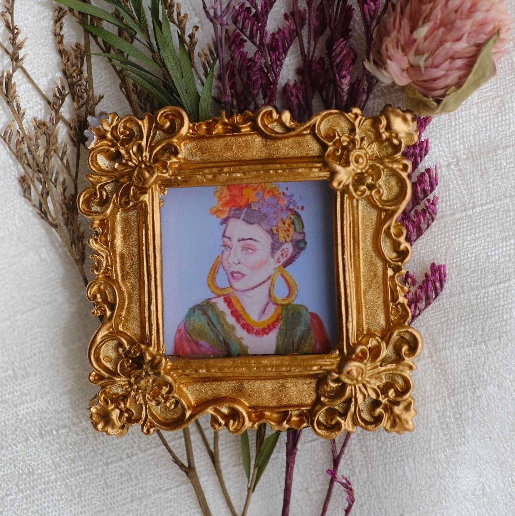 A painting of Frida Kahlo in a framed magnet.