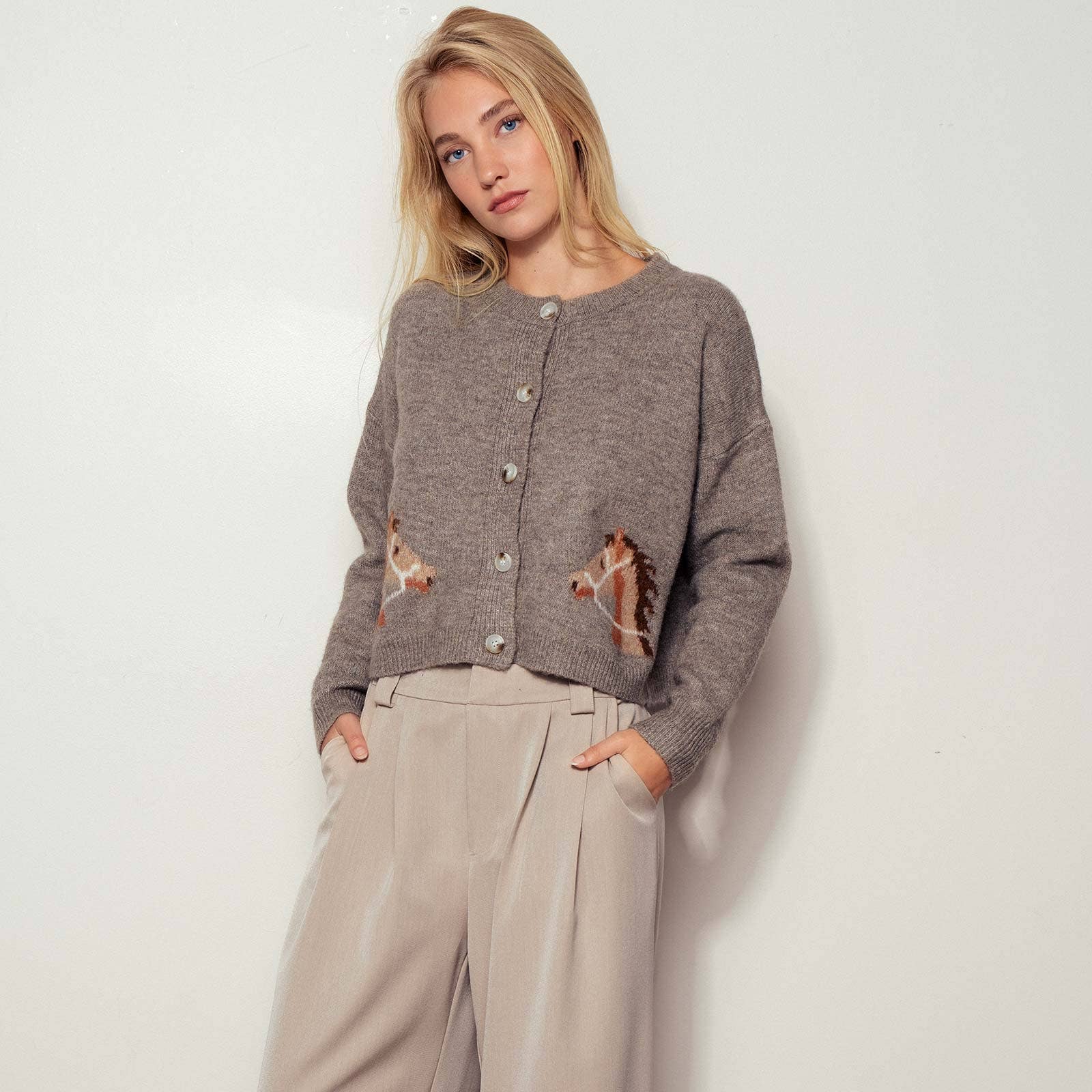 Mocha knitted cardigan with horse designs on a hanger against a light background