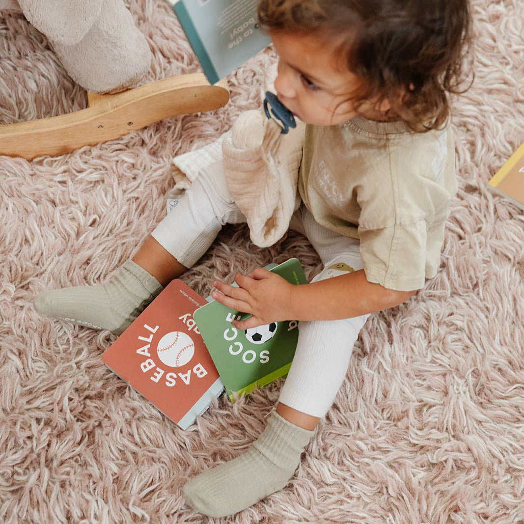 Child sitting on a fluffy pink carpet with books