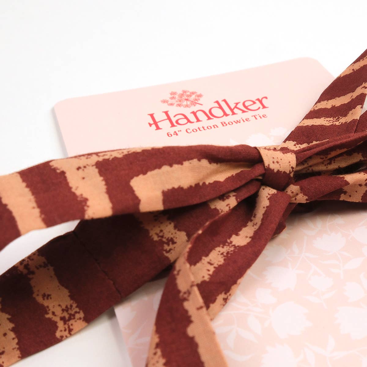 Brown and beige striped bow tie on a white background with 'Handker' branding.