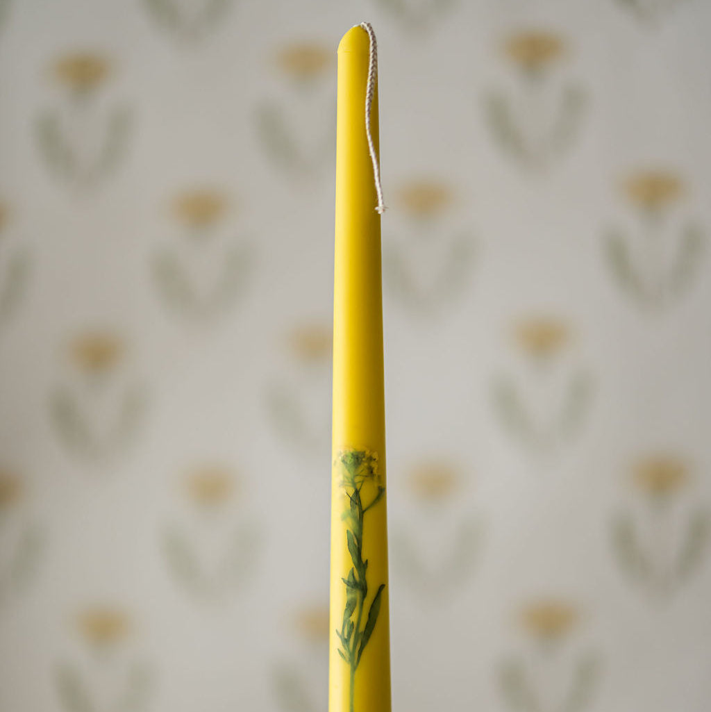a floral inlaid taper candle in a candlestick holder