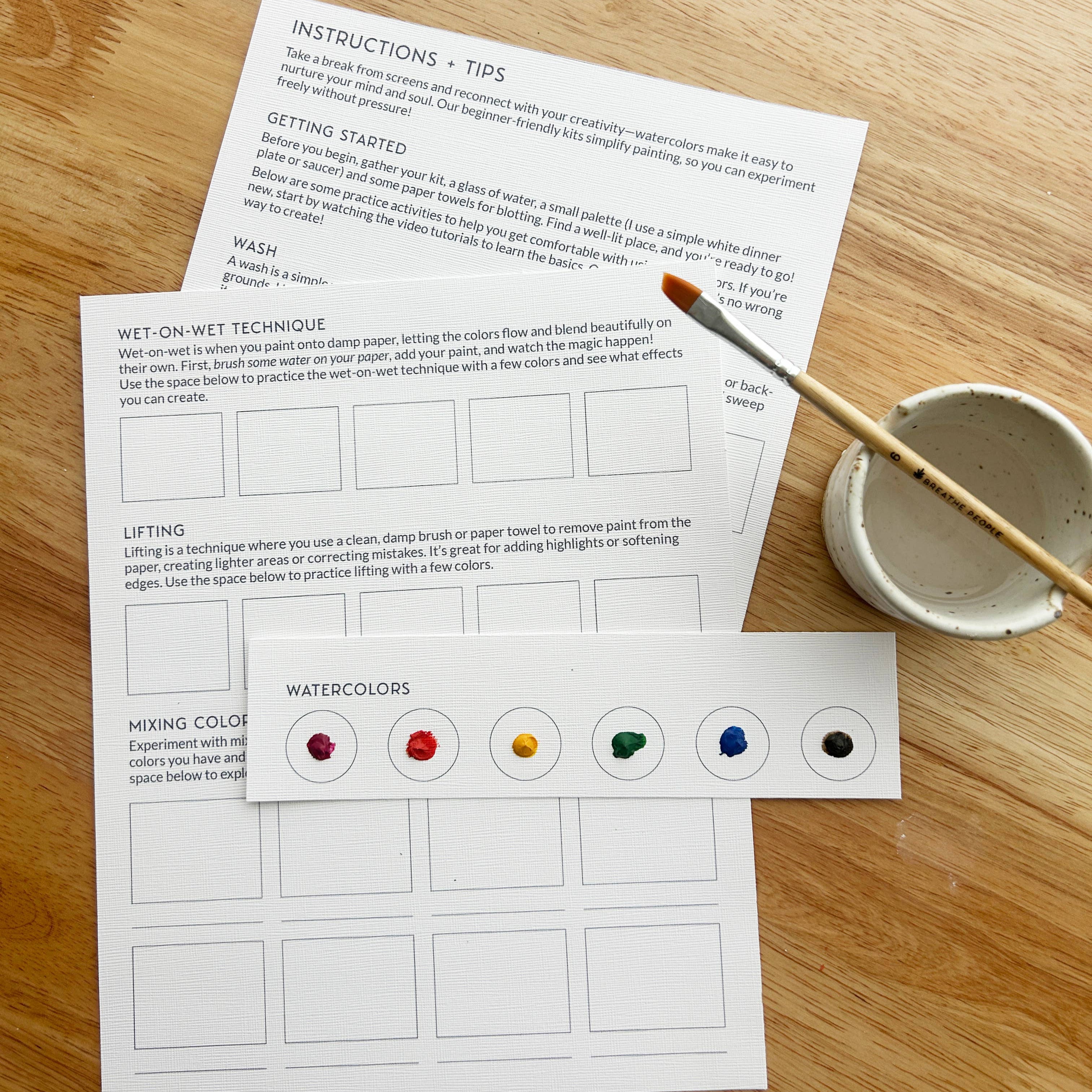 Art instruction sheet with paintbrush and water container on a wooden surface