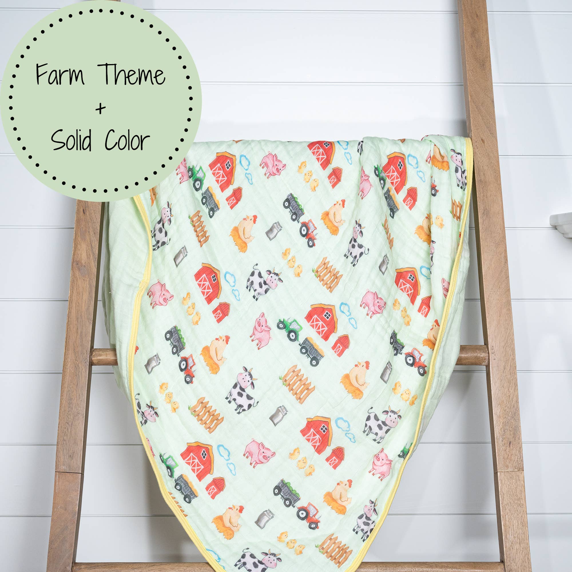 Baby blanket with farm-themed design on a wooden ladder against a white background