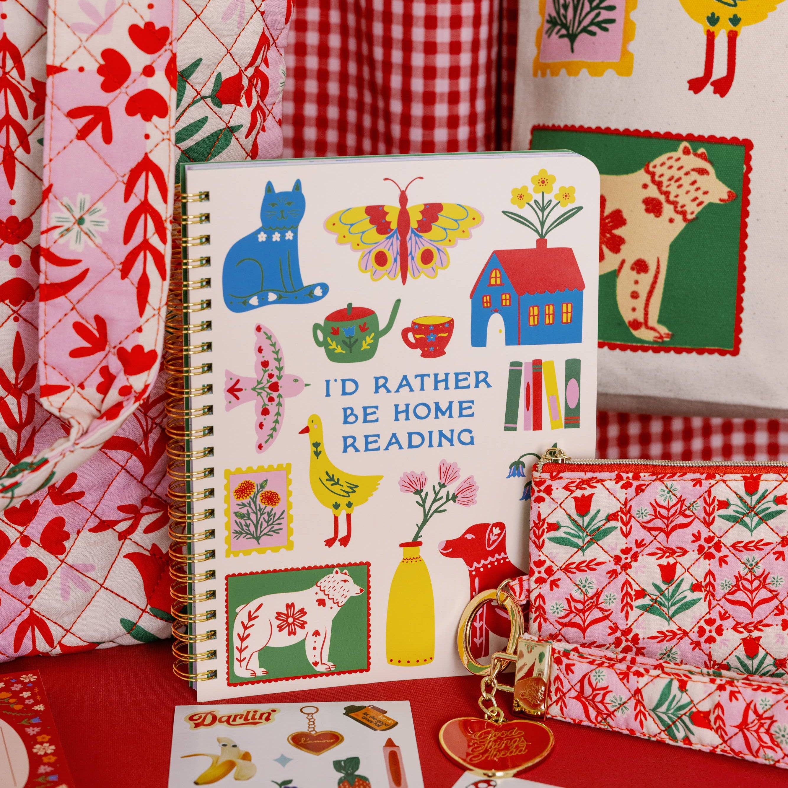 Colorful stationery items including a notebook, pouch, and fabric with animal patterns on a red checkered background.