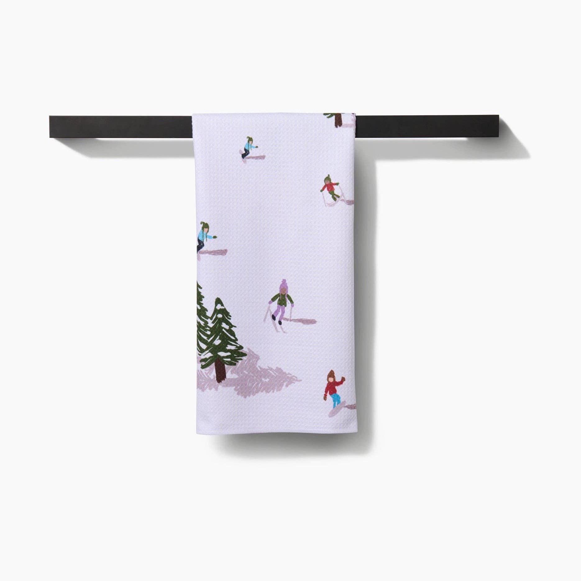Towel with winter scene design hanging on a black rod against a white background