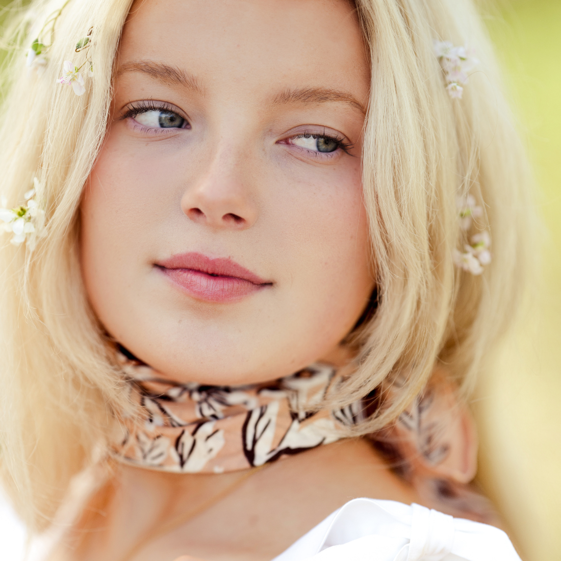 Close-up of a person with blonde hair and a patterned scarf, with a blurred background.