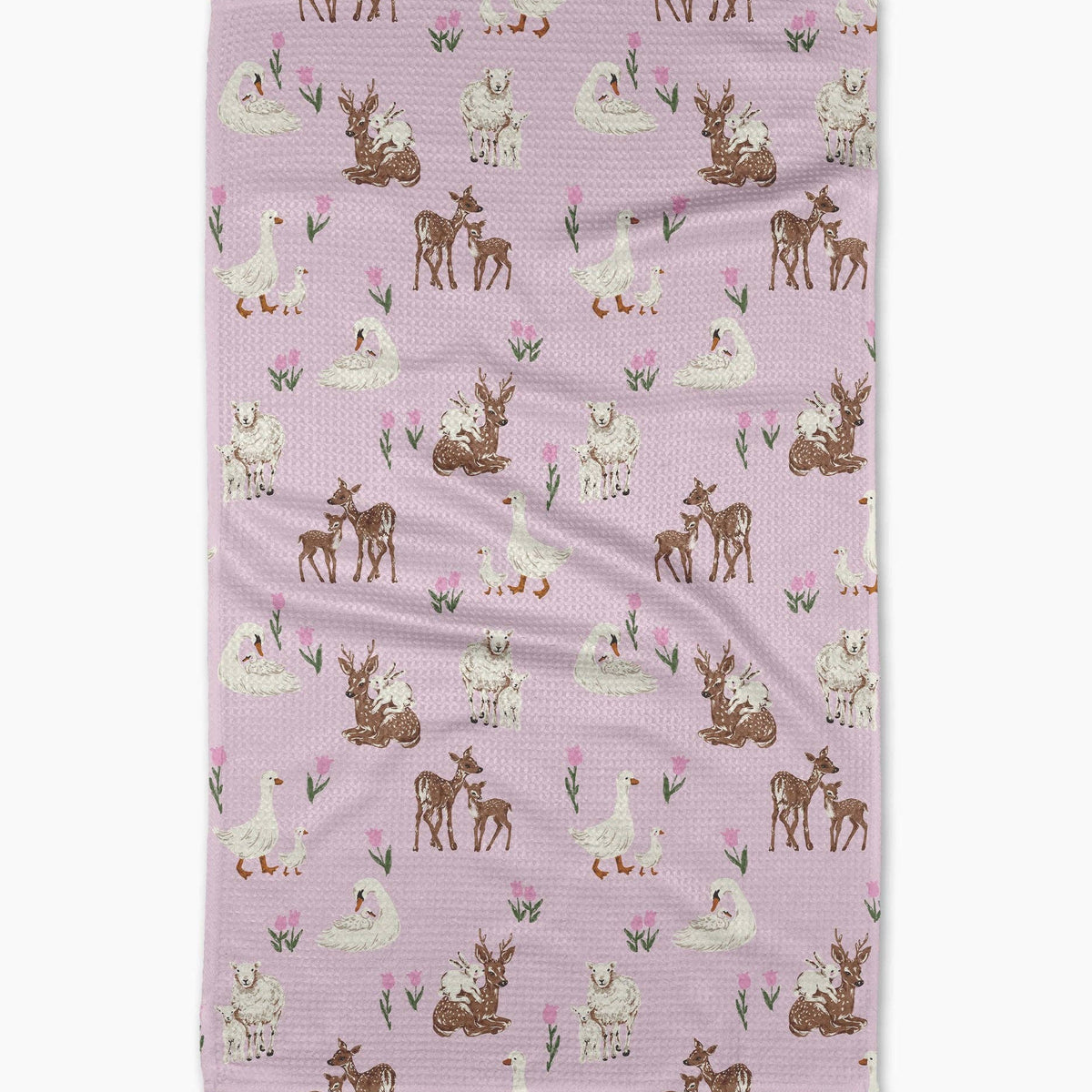 A rectangular waffle-weave tea towel with a repeating woodland pattern of deer, ducks, and flowers on a dusty pink background, shown flat against a white background.