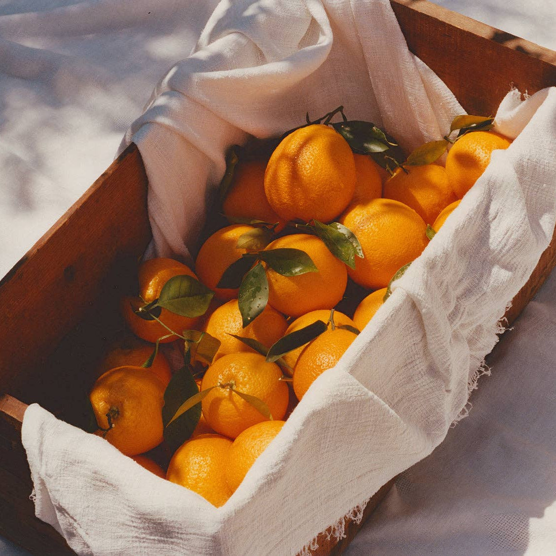 Oranges in a wooden box with a white cloth on a snowy background