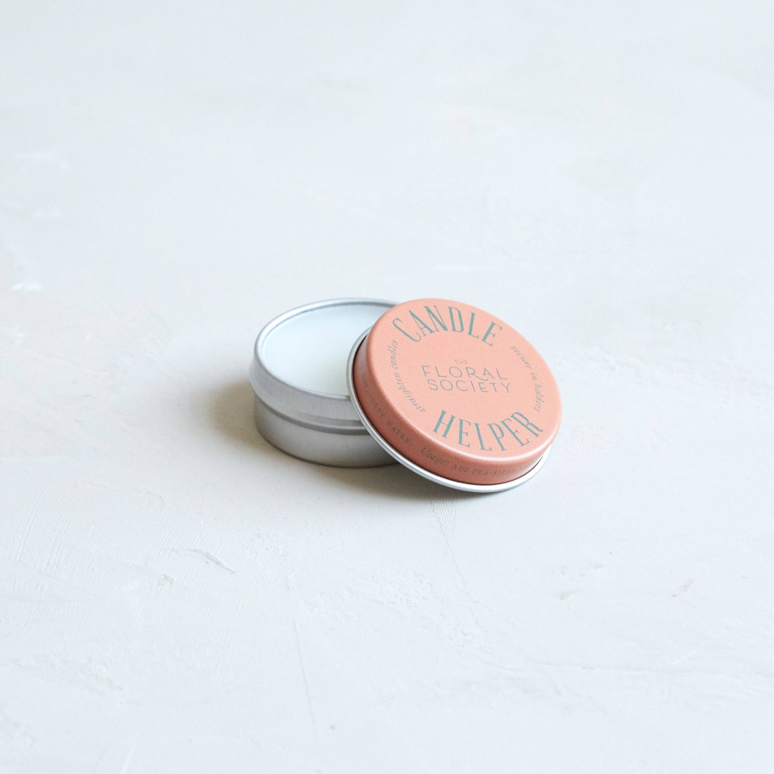 Small cylindrical container with a pink lid on a light gray background
