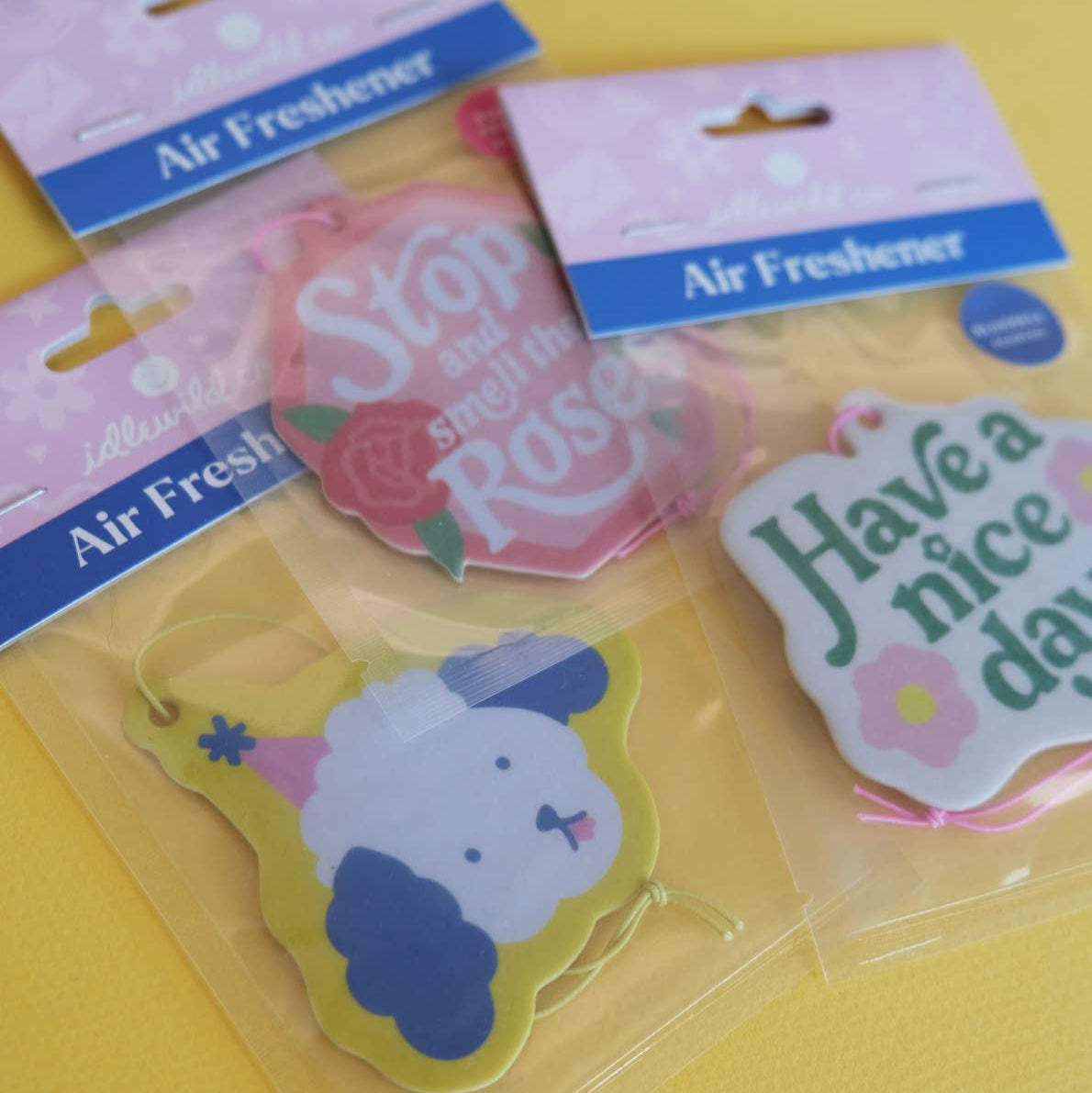 Pink hexagonal air freshener with 'Stop and smell the Roses' text and roses on a white background
