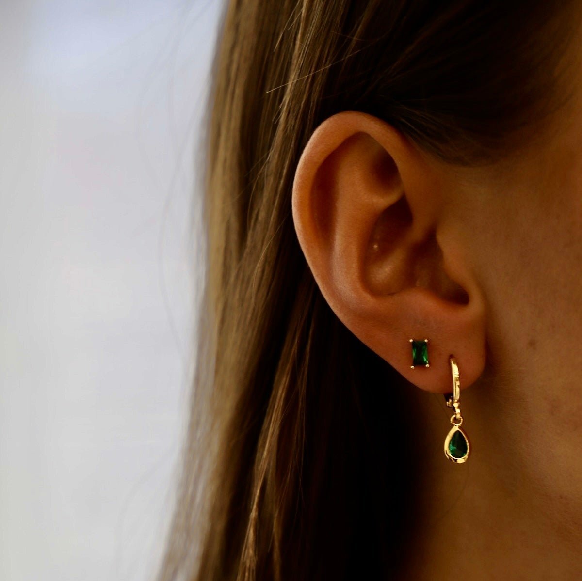 Our Emerald CZ Studs are glamorous and classic. With a baguette cut emerald jewel sitting on a sterling silver post they have just the right amount of colorful sparkle. They are easy to use as a layering piece in your first or second earring hole!