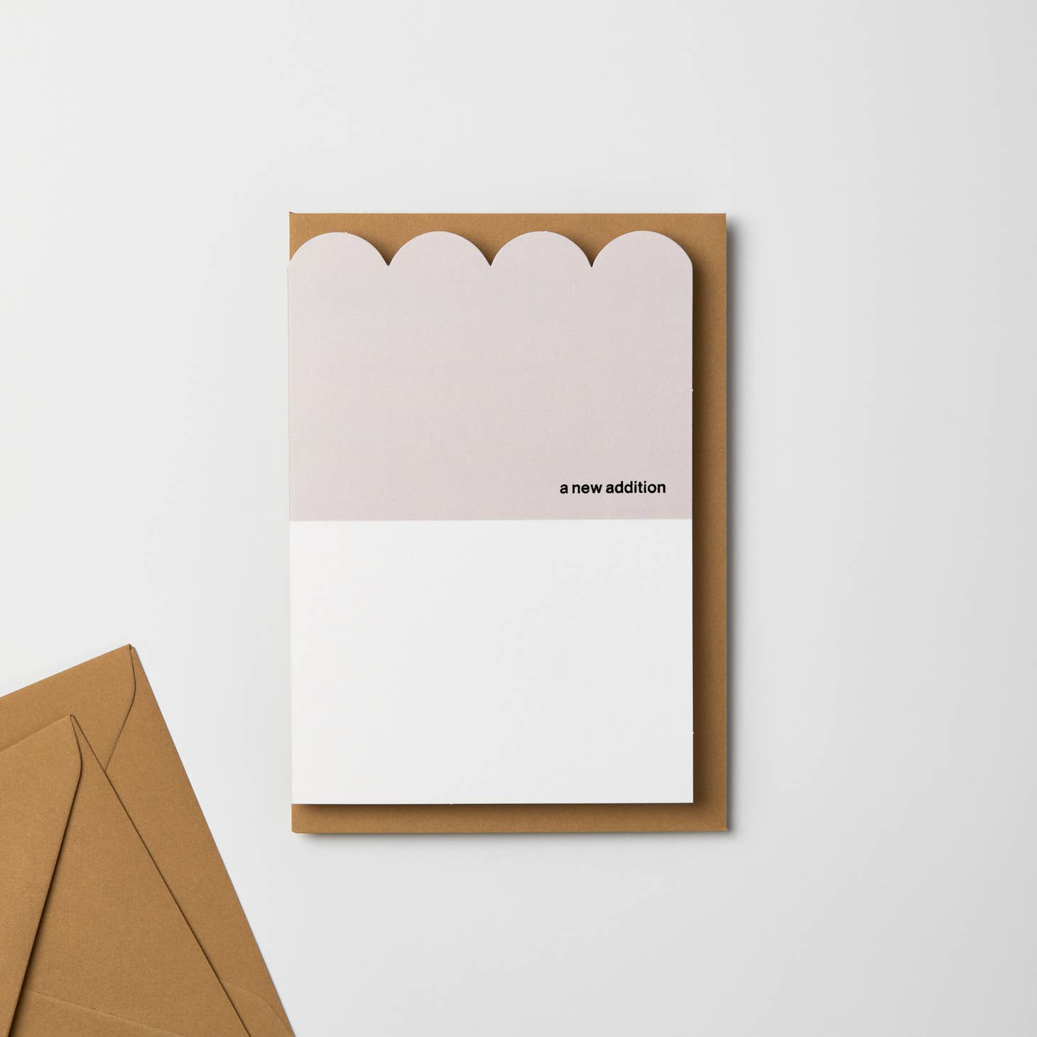 A beautiful, scalloped greeting card with a warm neutral grey color, featuring a black foiled 'a new addition'. These cards are printed on fsc board and accompanied with a gorgeous, luxury, flecked envelope which features 40% pcw.