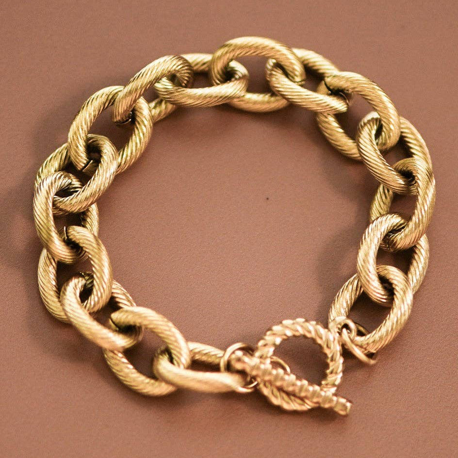 Elevate your everyday style with this striking 18K gold plated chunky link chain bracelet. Crafted from hypoallergenic stainless steel, it features a textured toggle clasp for secure, effortless wear. Waterproof and tarnish-resistant, this versatile piece withstands daily activities and moisture exposure. To maintain its lustrous finish, minimize contact with lotions, perfumes, and cleaning products. A timeless accessory that combines durability with sophisticated design.