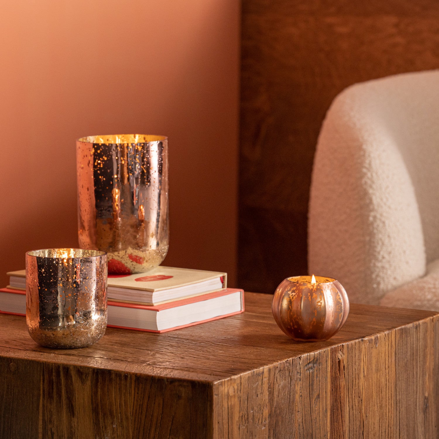 Three metallic candle holders on a wooden surface with a warm-toned background