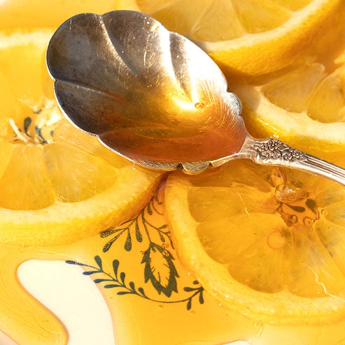 Spoon with honey on a background of sliced lemons