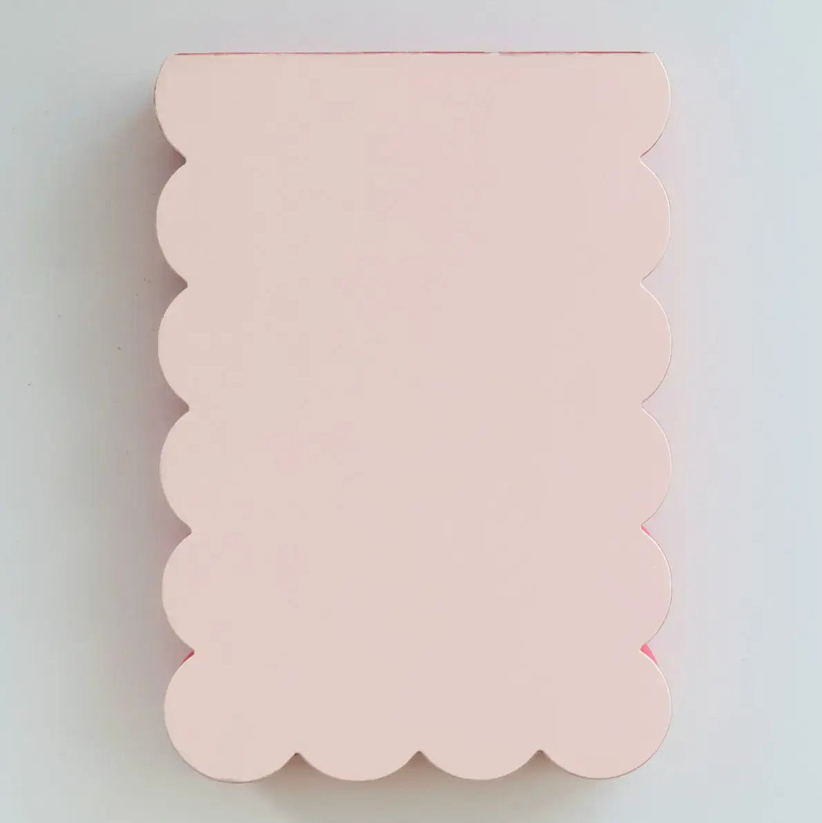 Pink scalloped object on a light gray background