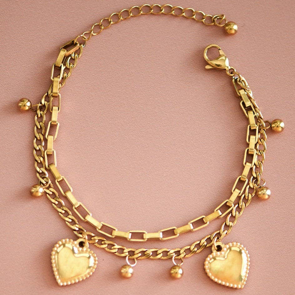 Elevate your everyday style with this 18K gold plated stainless steel chain bracelet, featuring delicate heart charms and gold ball accents. Crafted from hypoallergenic, waterproof, and tarnish-resistant materials, it's designed to withstand daily wear while maintaining its lustrous finish. Perfect for layering or wearing solo, this versatile piece combines durability with timeless elegance. To preserve the gold plating's brilliance, avoid prolonged contact with lotions, perfumes, and harsh chemicals.