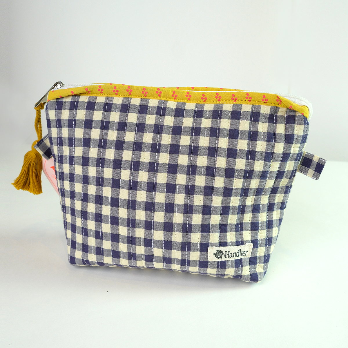 Blue and white checkered pouch with yellow trim and tassel on a light gray background