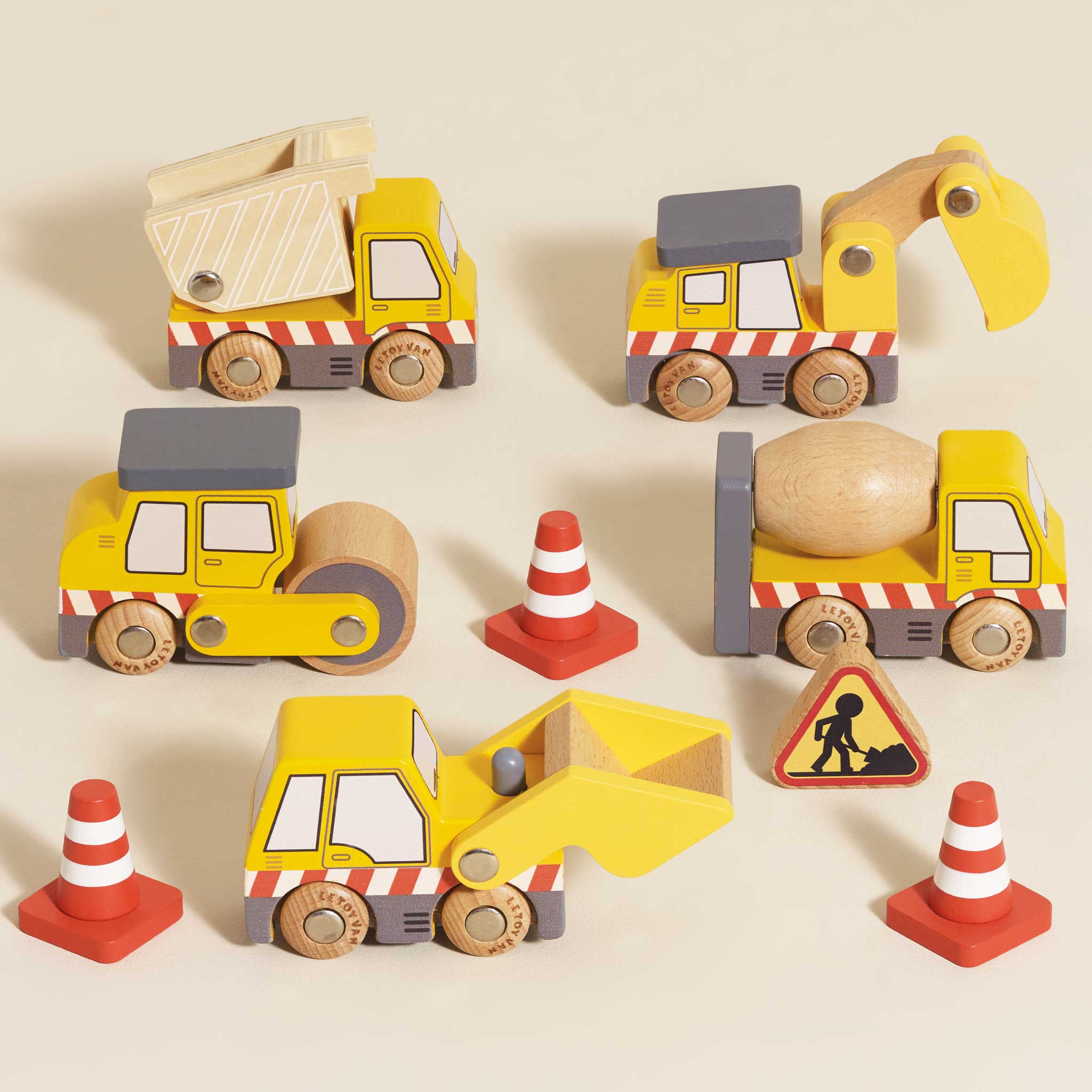 Set of wooden toy construction vehicles on a beige background