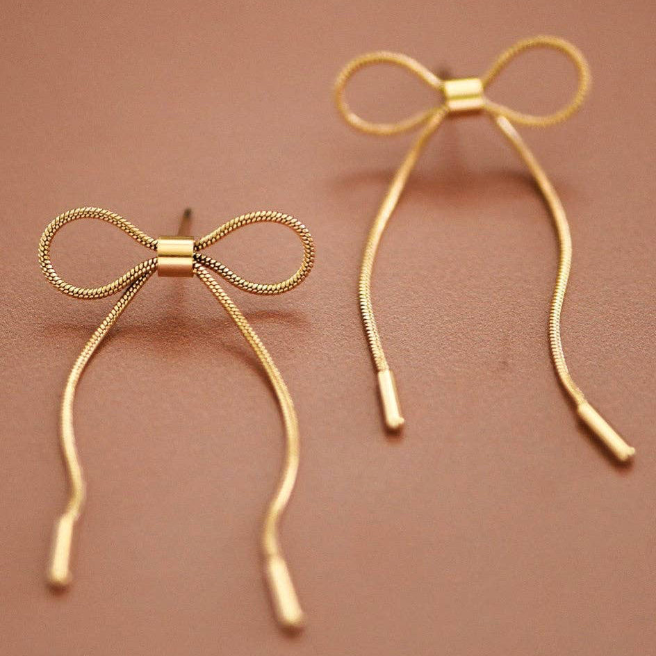 Elegant 18K gold plated stud earrings featuring a delicate bowknot design. Crafted from hypoallergenic stainless steel, these versatile pieces are waterproof and tarnish-resistant, making them perfect for everyday wear. Measuring approximately 0.85" x 1.9", they offer a refined look that complements any style. To maintain their lustrous finish, avoid prolonged contact with lotions, perfumes, and harsh chemicals.