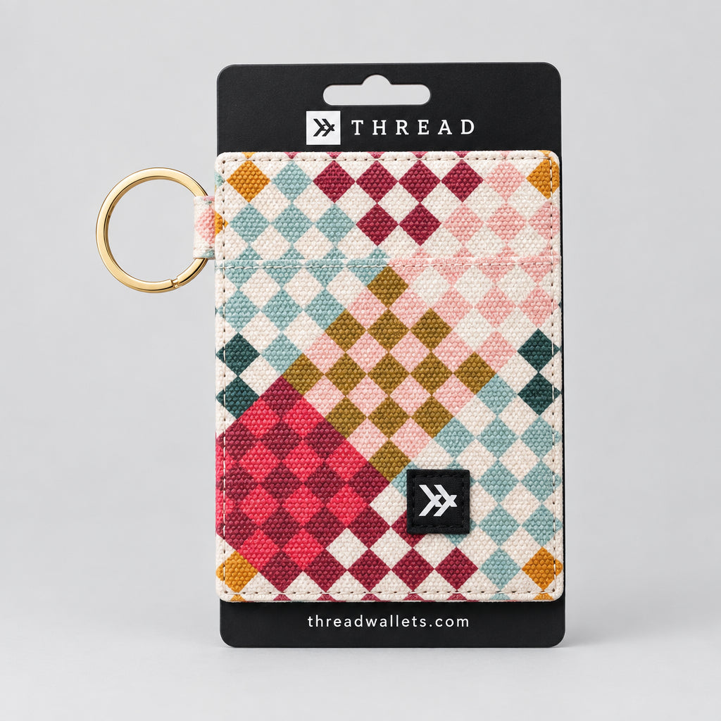 A Thread brand cardholder wallet featuring a colorful geometric diamond pattern in pink, red, blue, green, and gold on a white background, with a black top and bottom trim and a gold keyring attached.