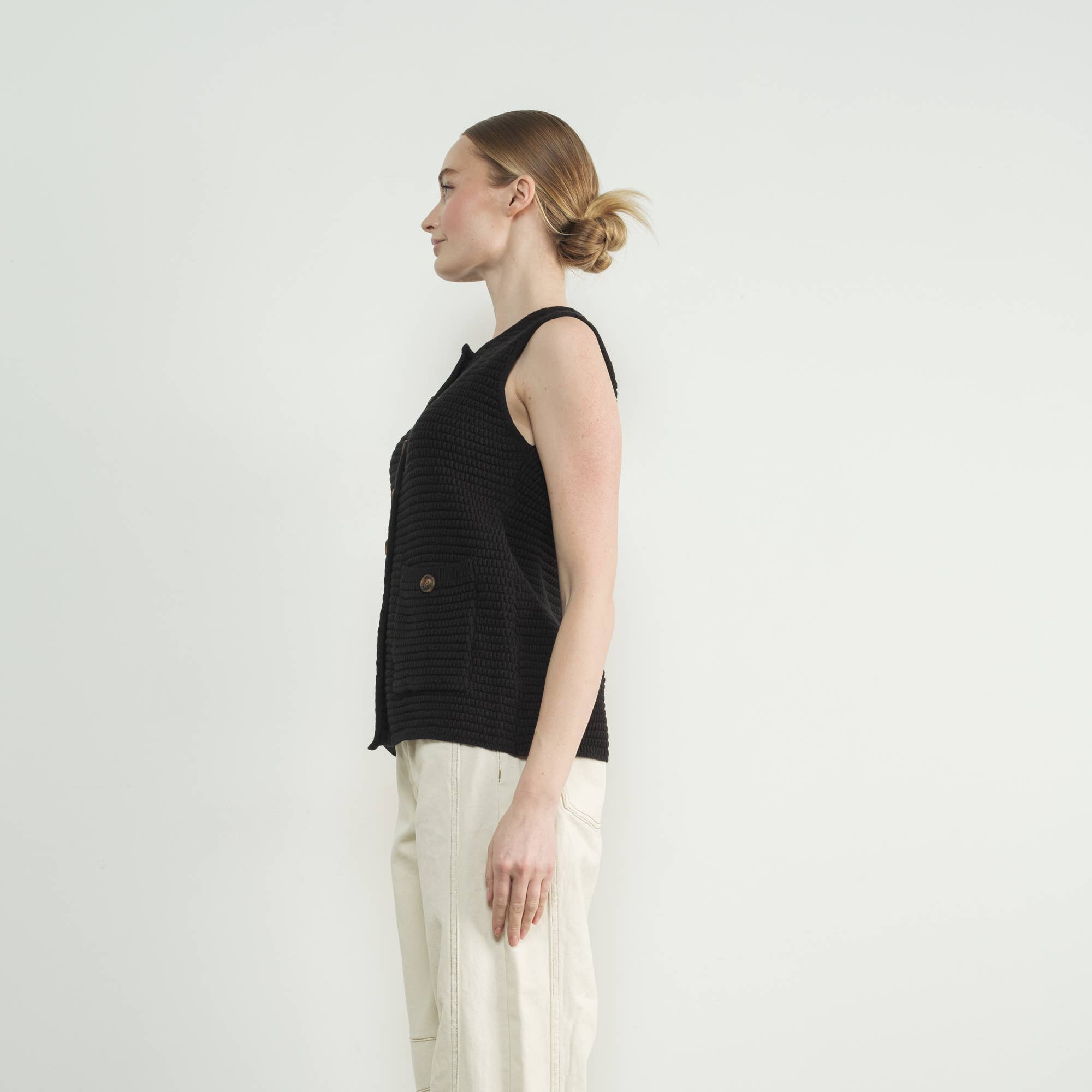 This black sweater vest is the epitome of cozy-chic style, featuring allover ribbed texture and classic button-up closure for a refined yet modern aesthetic. Designed for versatility, it can be worn as a standalone statement. Fitted silhouette that beautifully enhances femininity and complements any outfit. 