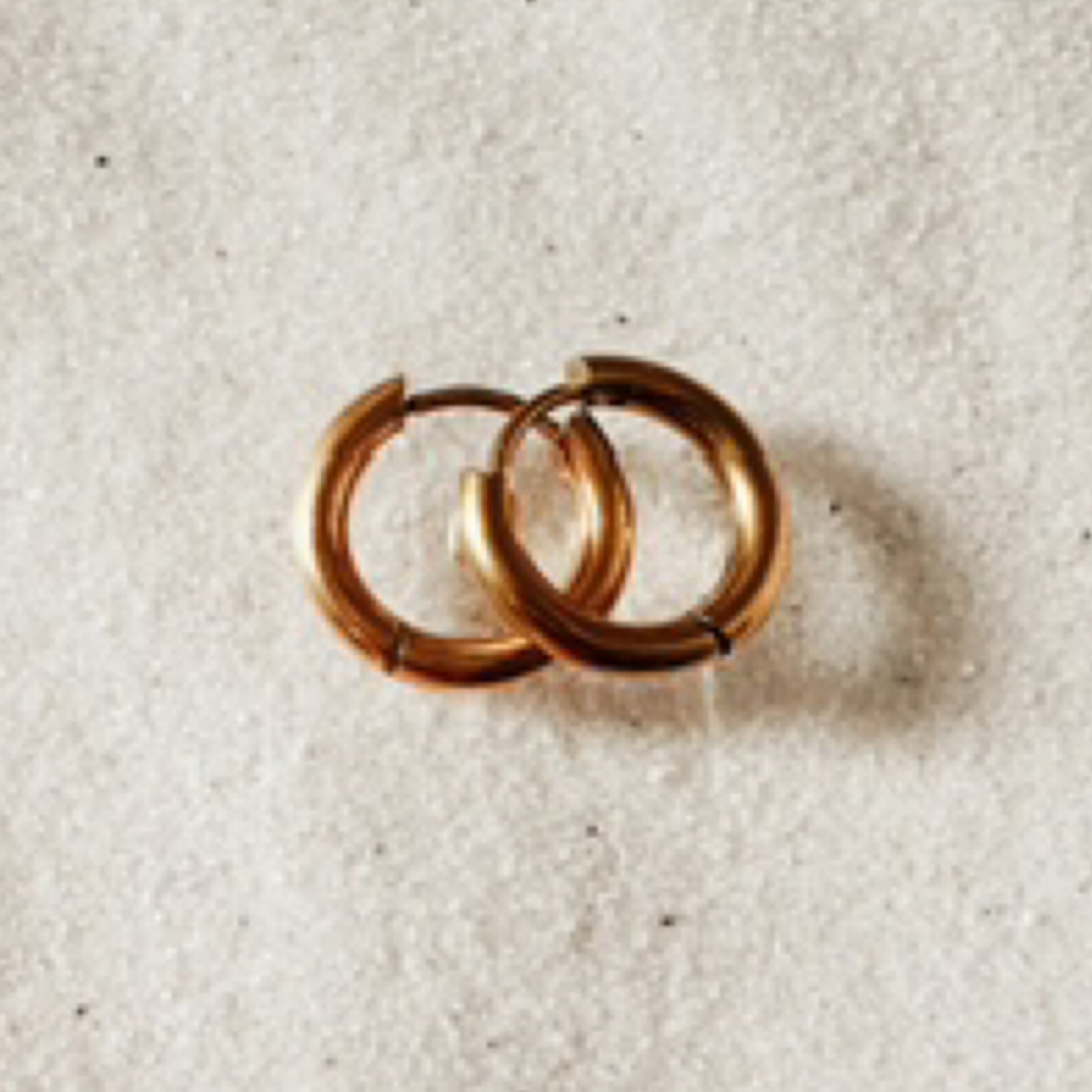 Simple gold hoops against white sand.