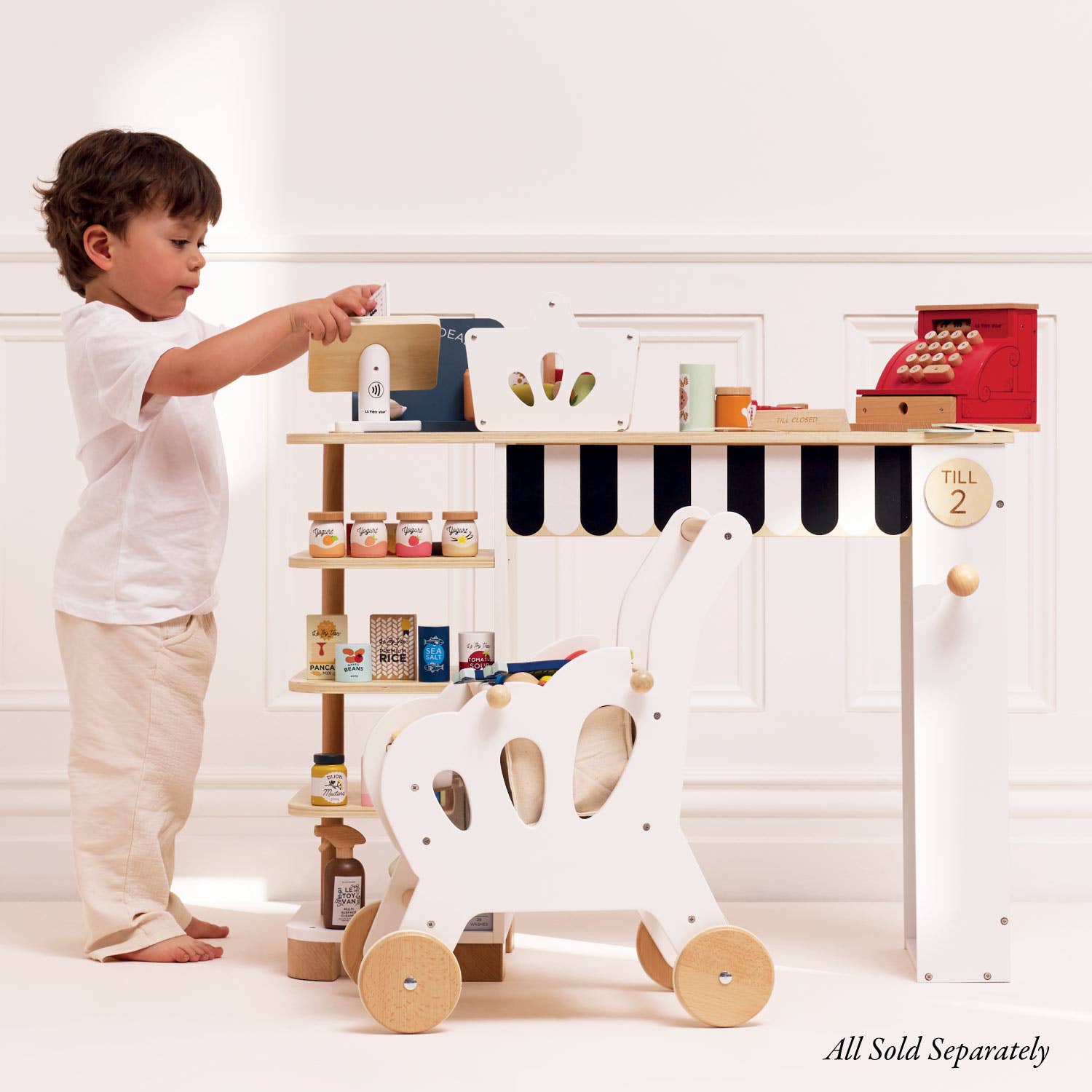 Child playing with a toy kitchen set on a white shelf