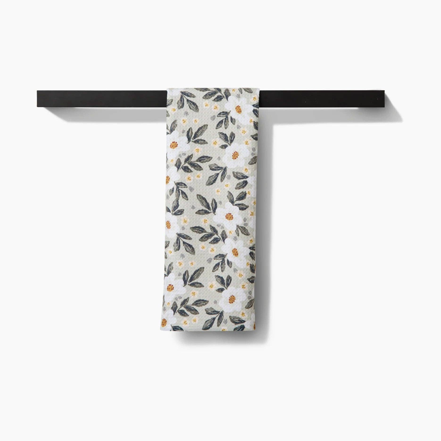 Floral-patterned towel hanging on a black rack against a white background