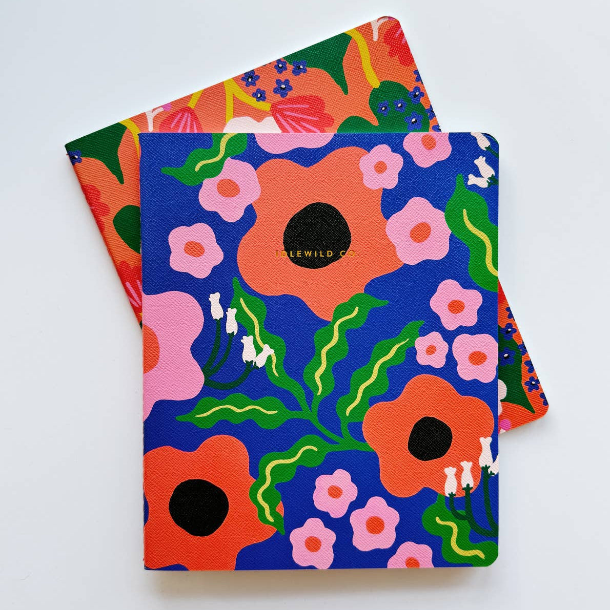 Two colorful notebooks with floral designs on a white background
