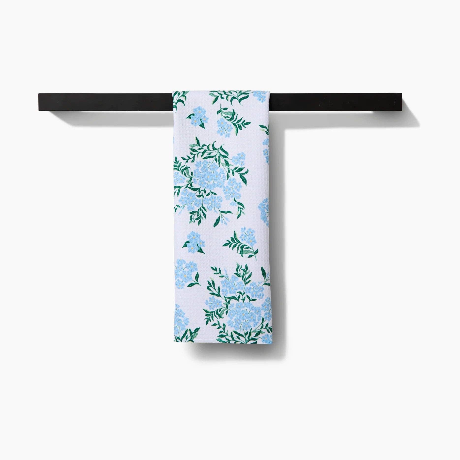 Floral-patterned towel hanging on a black metal rack against a white background