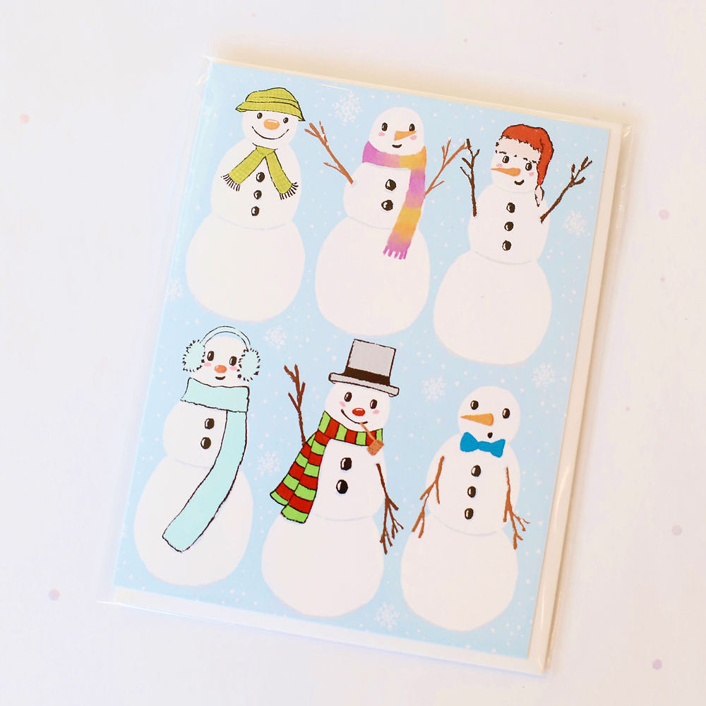 Light blue card with white snowmen in various hats and scarves holding hands and smiling. Pictured against a white back ground.