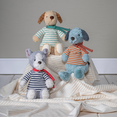 Three stuffed animals in striped shirts on a textured surface with a neutral background