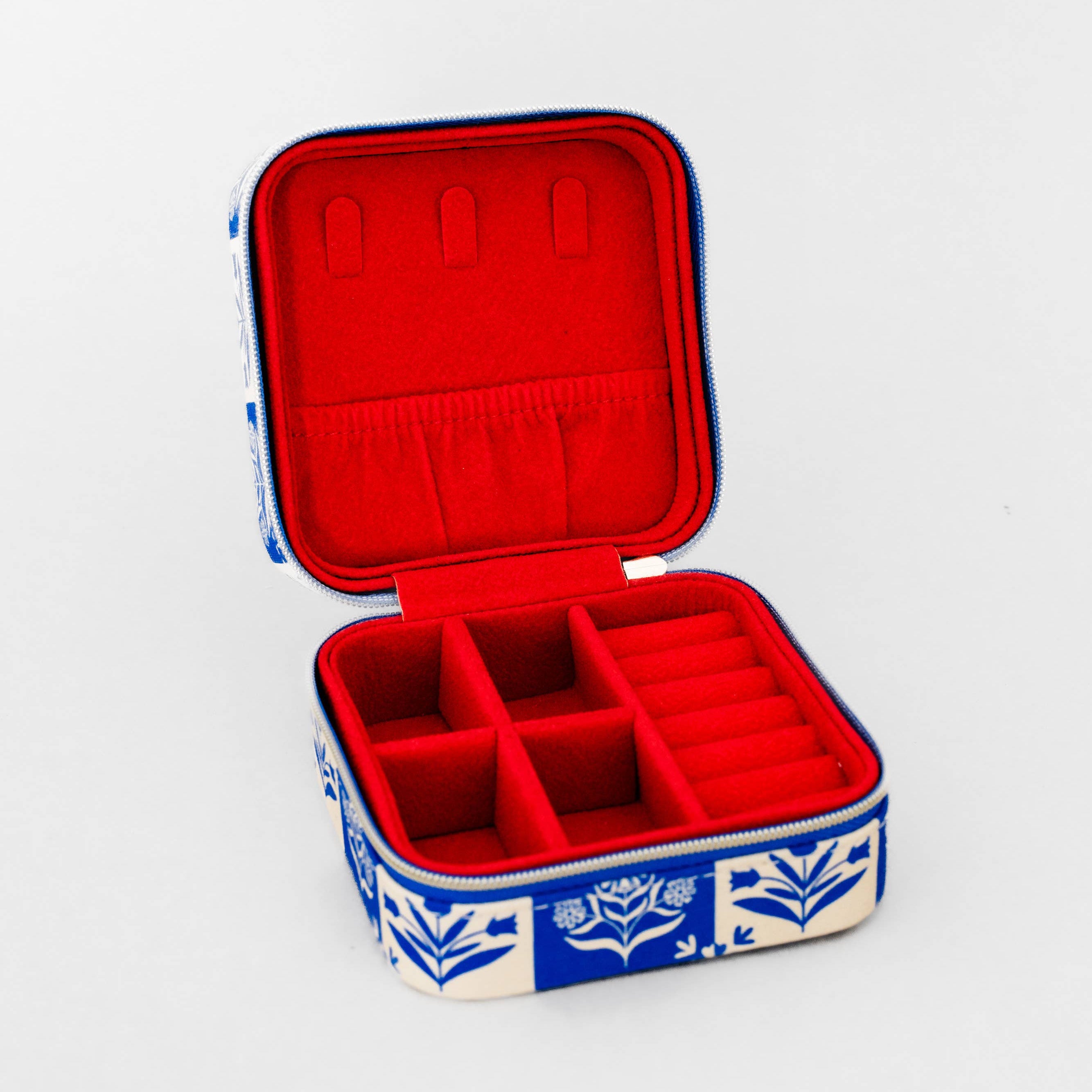 An open square jewelry organizer case with a red velvet interior and a blue and white floral patterned exterior, shown on a plain white background.
