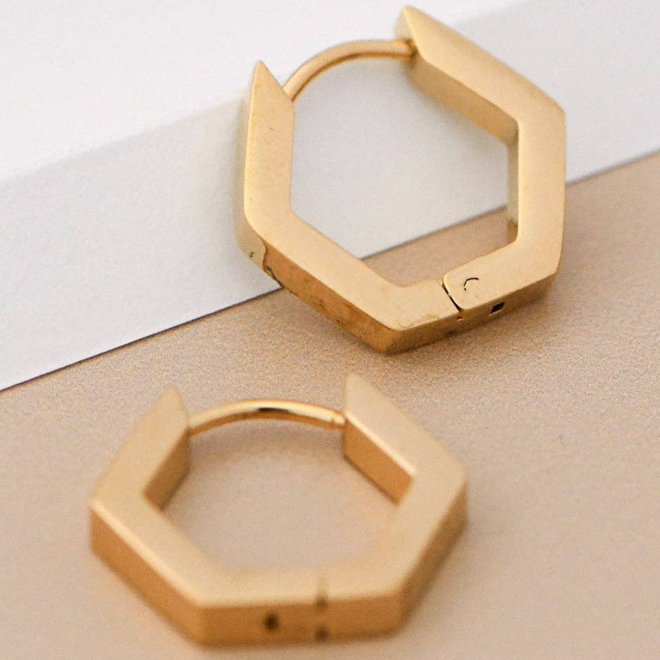Elevate your everyday look with these 18K gold plated stainless steel hoop earrings, featuring a striking hexagon design. Measuring approximately 0.6" in length, these versatile earrings combine style with durability. Hypoallergenic and waterproof, they're perfect for sensitive skin and active lifestyles. The tarnish-resistant finish keeps them looking radiant longer. To maintain their lustrous shine, avoid prolonged contact with lotions, perfumes, and cleaning products.