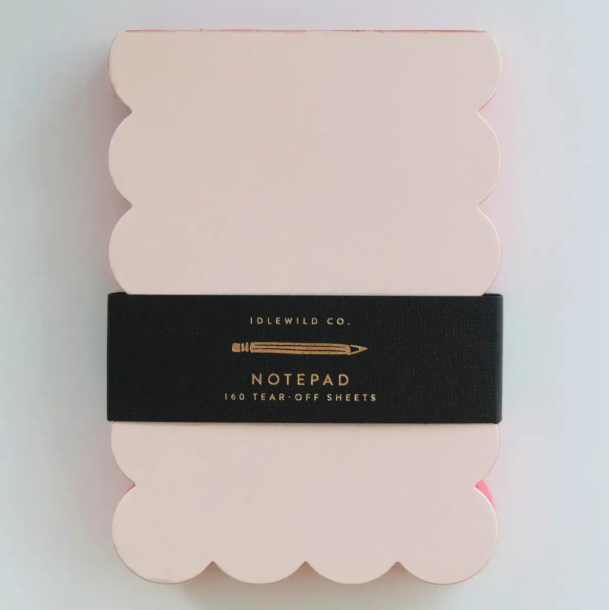 Packaged notepad with scalloped edges on a light gray background