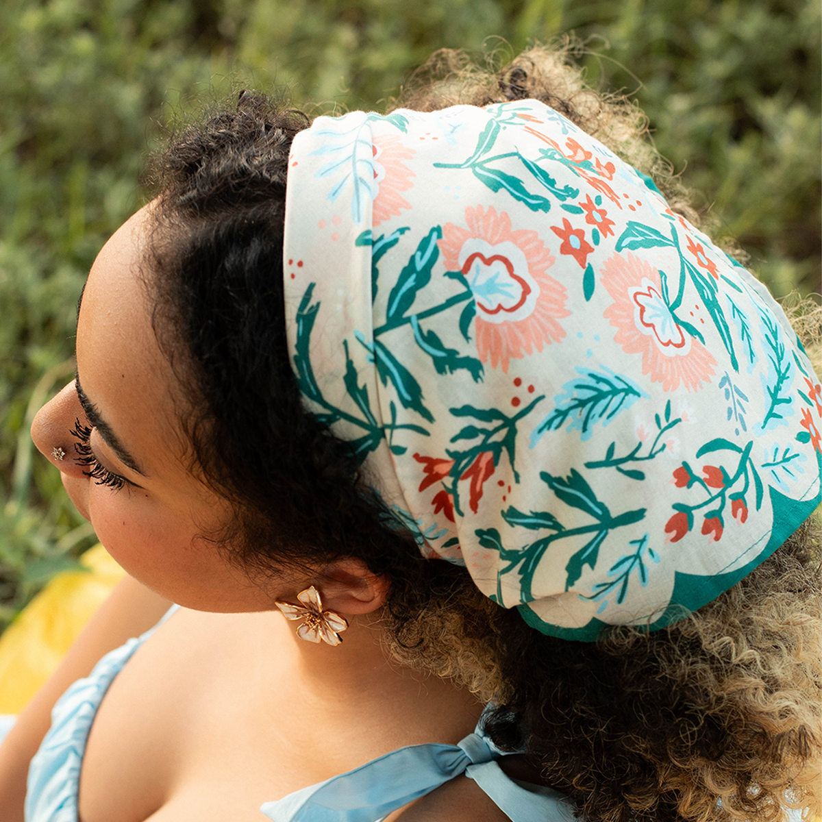 Person wearing a floral headscarf with a blurred green background