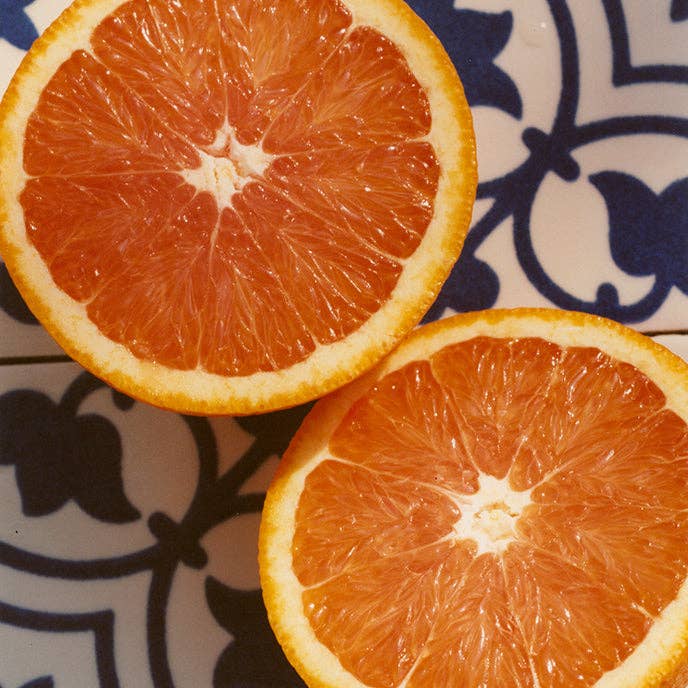 Two halves of an orange on a decorative blue and white plate