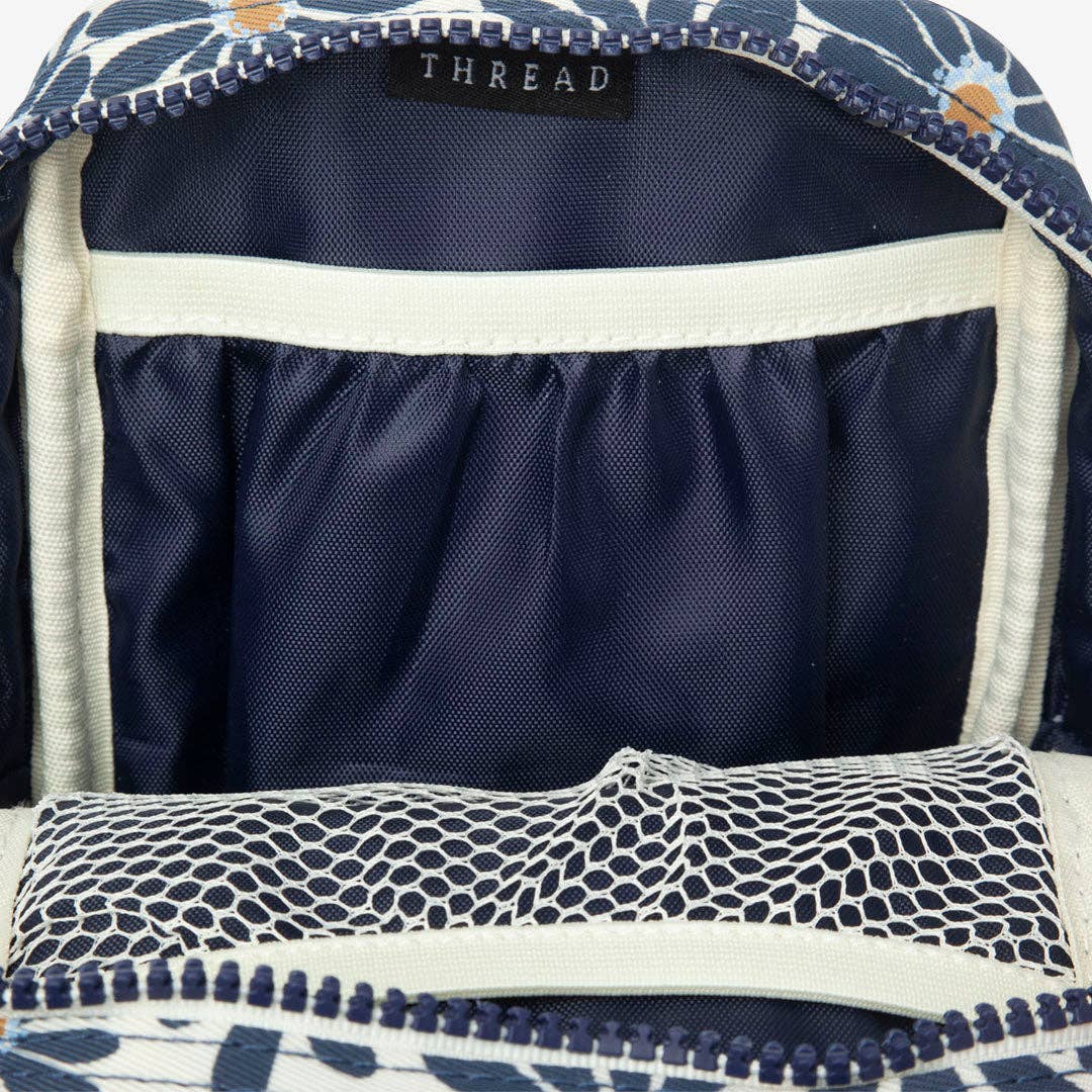 Navy blue backpack with floral pattern on top, open to reveal interior.