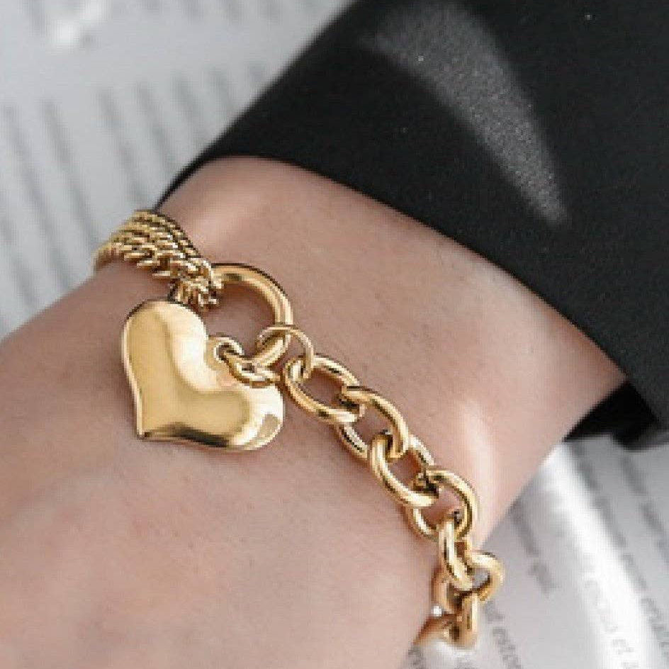 Elevate your everyday style with this 18K gold plated stainless steel chain bracelet, featuring a chunky heart charm. Crafted from hypoallergenic materials, it's perfect for sensitive skin and designed to withstand daily wear with its waterproof and tarnish-resistant properties. The lustrous gold finish maintains its brilliance when kept away from lotions, perfumes, and harsh chemicals. A timeless accessory that combines durability with elegant sophistication.