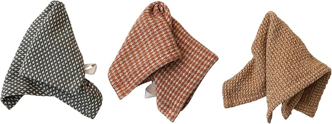 Folded dish towels in brown, green, and orange on a textured white surface