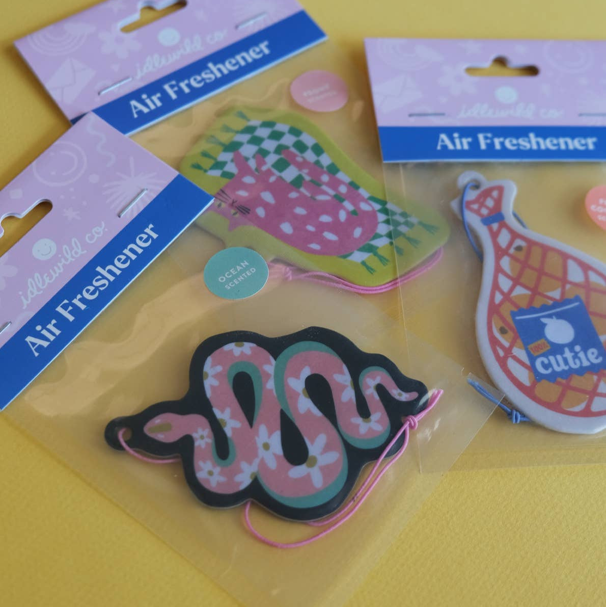 Three air freshener designs on a yellow background