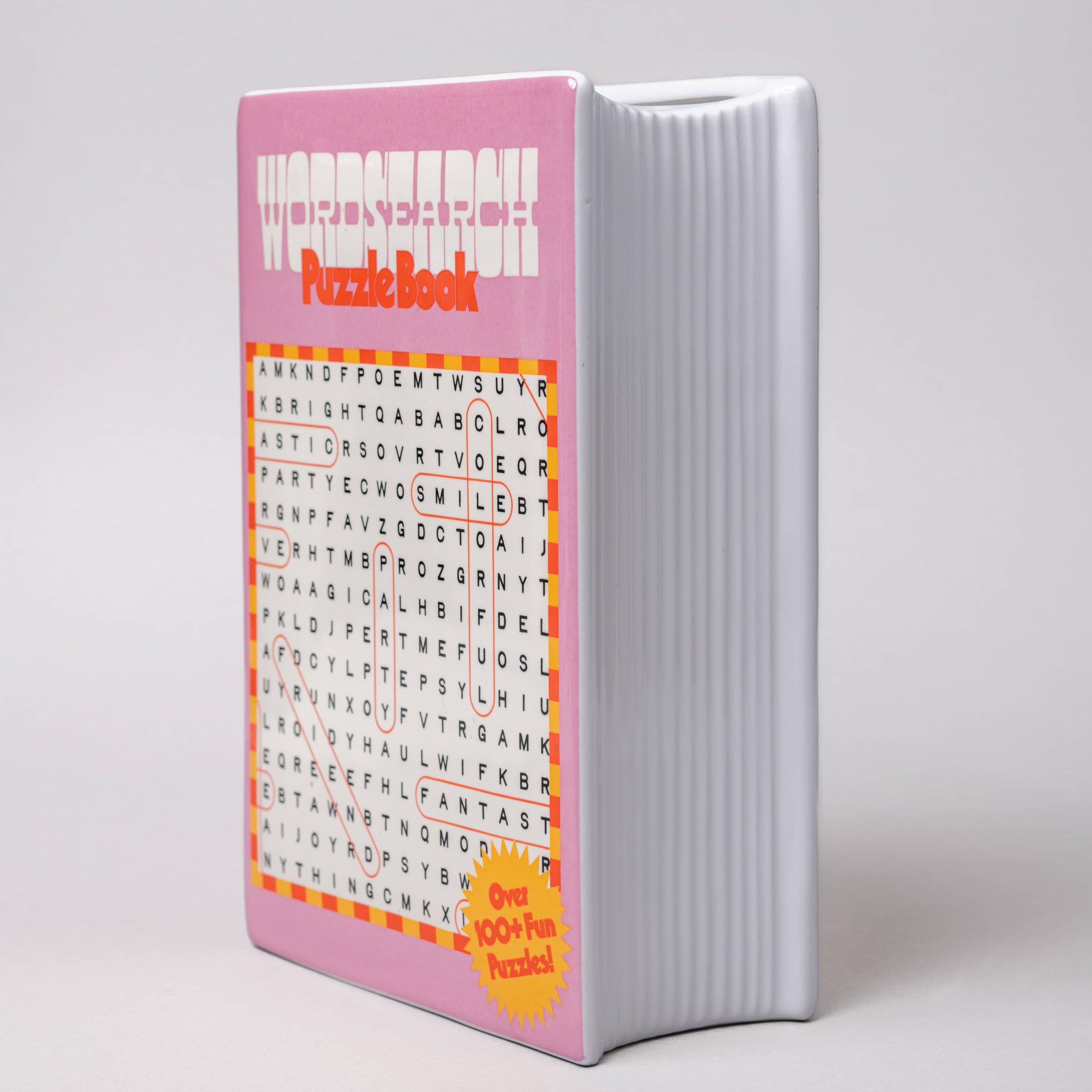 Pink puzzle book vase with word search design on a gray background
