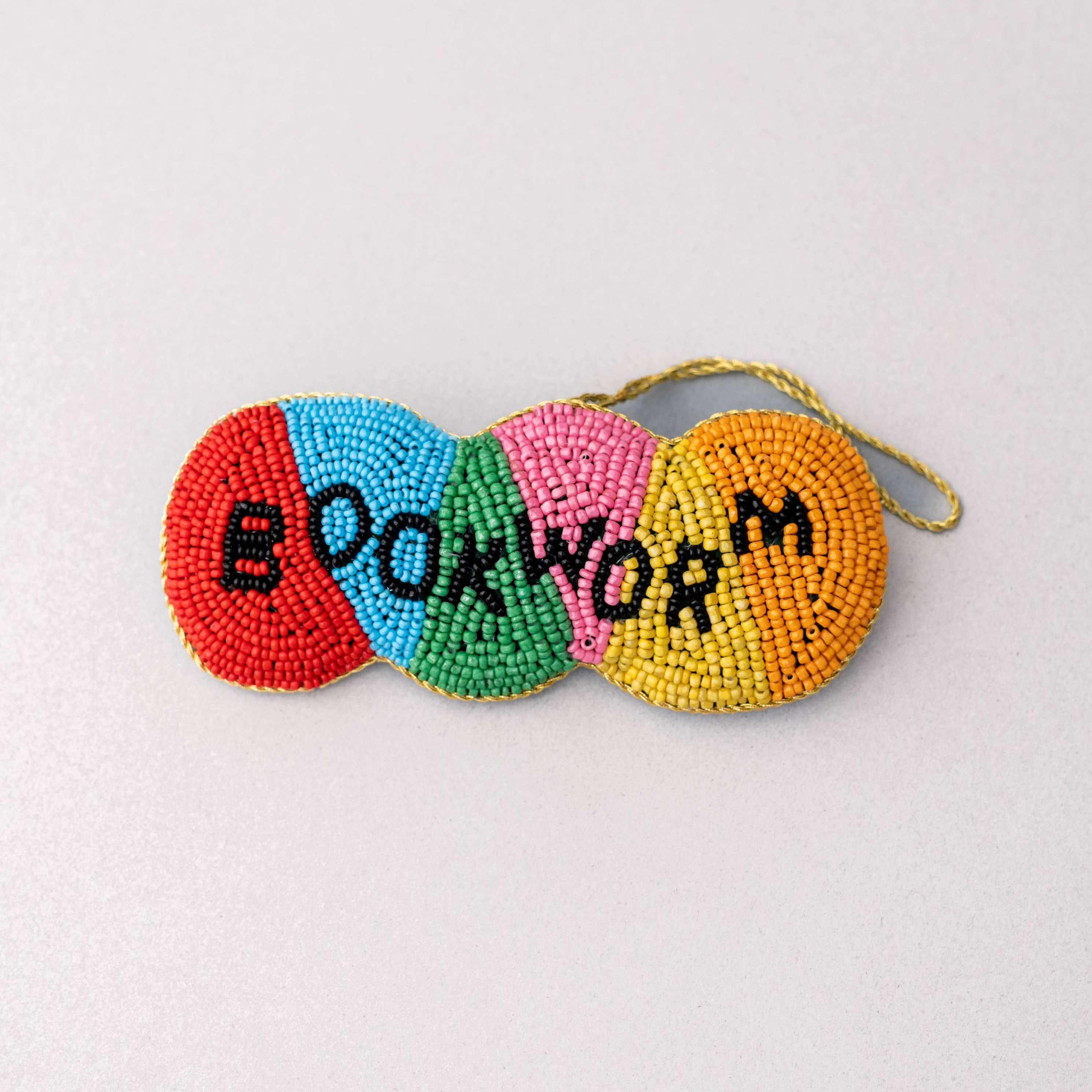 Colorful beaded ornament with 'BOOKWORM' text on a light gray background