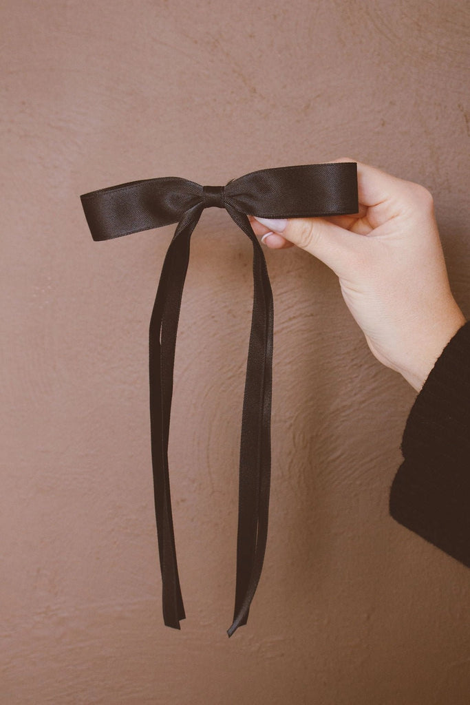 Introducing our Black Satin Ribbon Long Bow Clip! Featuring extra long tails and a secure alligator clip, this bow is perfect for adding a touch of elegance to any outfit. Plus, its neutral black color is versatile and will match any style. Get ready to make a statement (with style) wearing this bow!