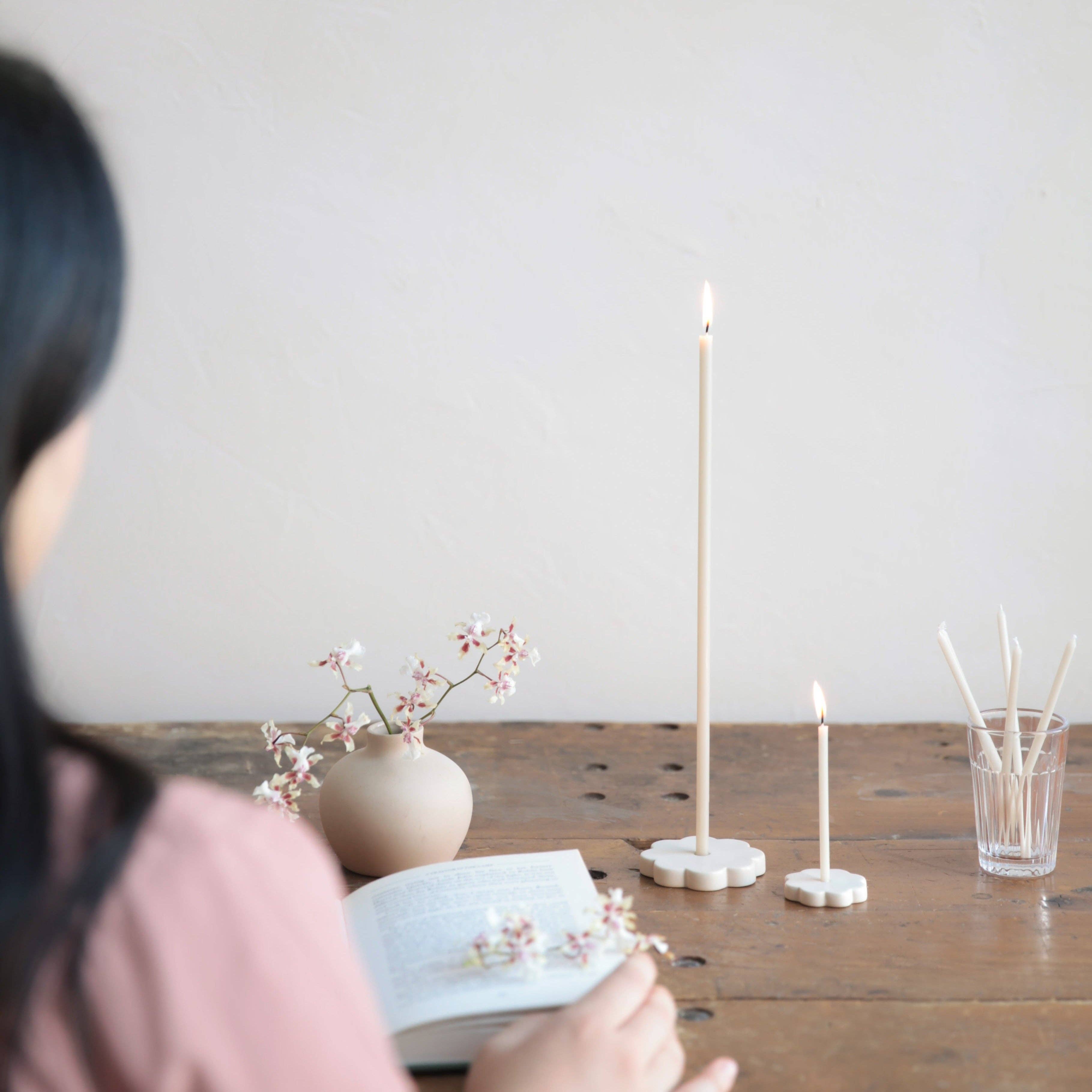 Person reading a book with candles and flowers on a wooden table