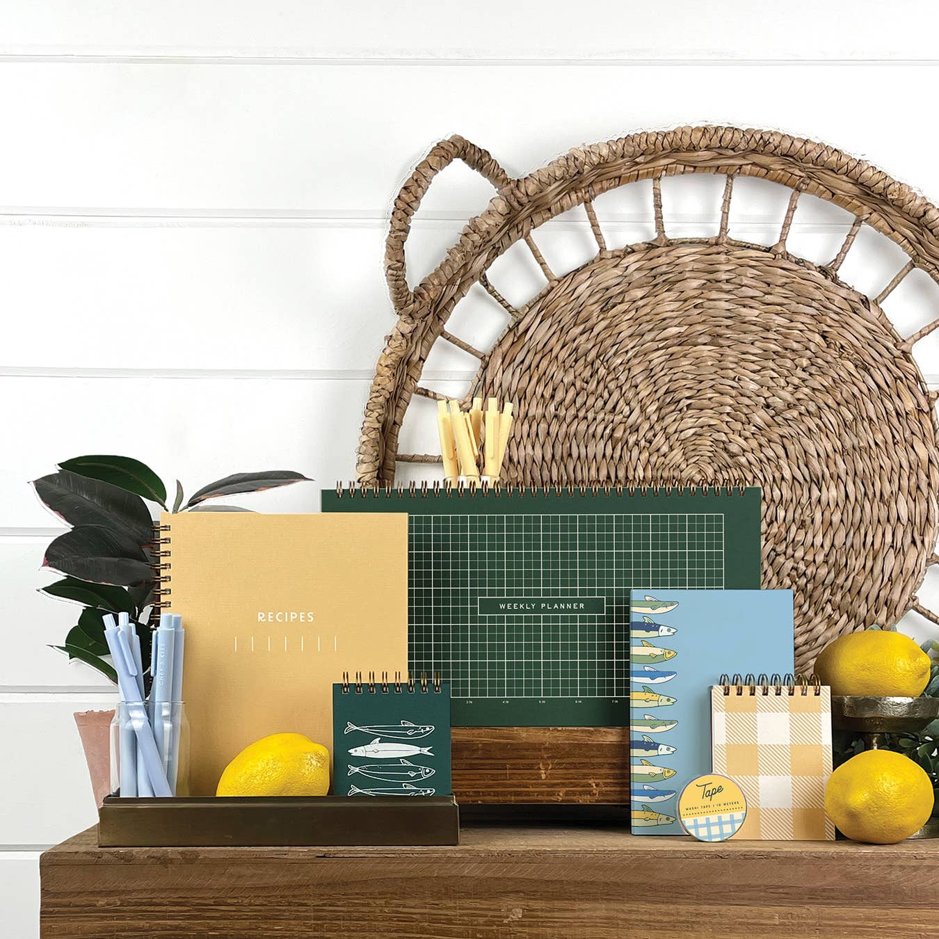 Collection of planners, notebooks, and decorative items on a wooden surface with a wicker basket in the background.