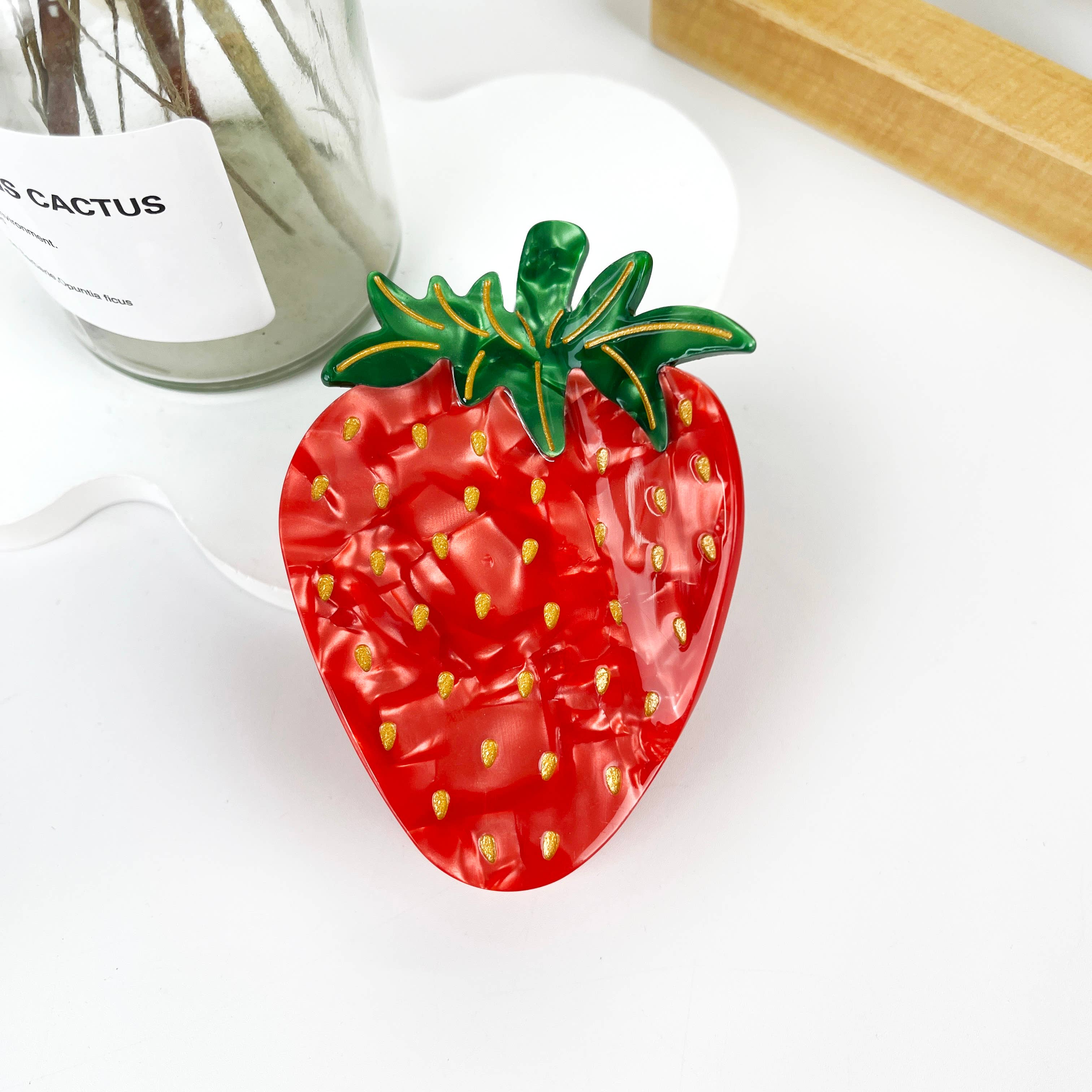 Elevate your hairstyle with the sweet charm of our Strawberry Fruit Hair Clip. This delightful accessory brings a touch of nature's freshness to your look, perfect for adding a playful and vibrant accent to any outfit.
This clips bright red color and green leafy top capture the essence of a ripe strawberry, making it an eye-catching addition to your accessory collection.